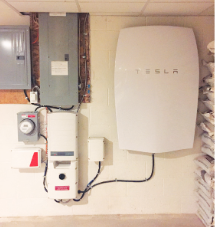 Tesla Powerwall battery (right) with inverter, solar meter and main electrical box in basement of Rife solar home.